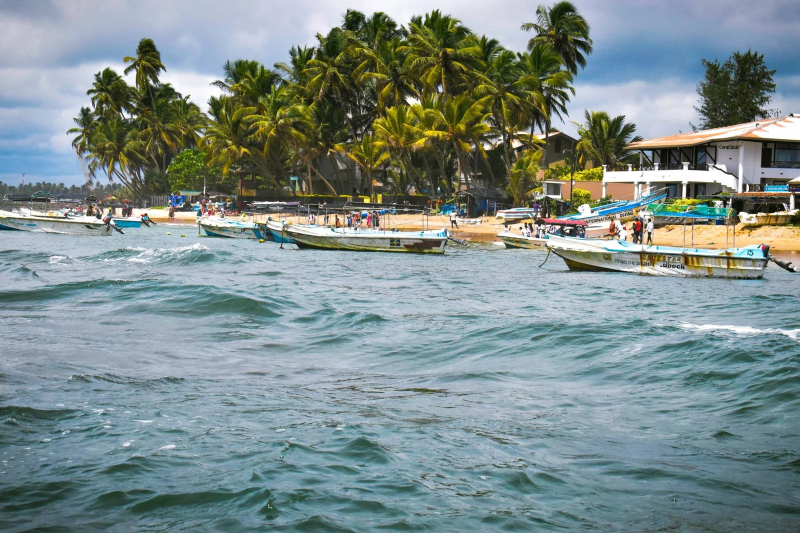 Boats near the palm-lined shore of Hikkaduwa Beach, Sri Lanka.